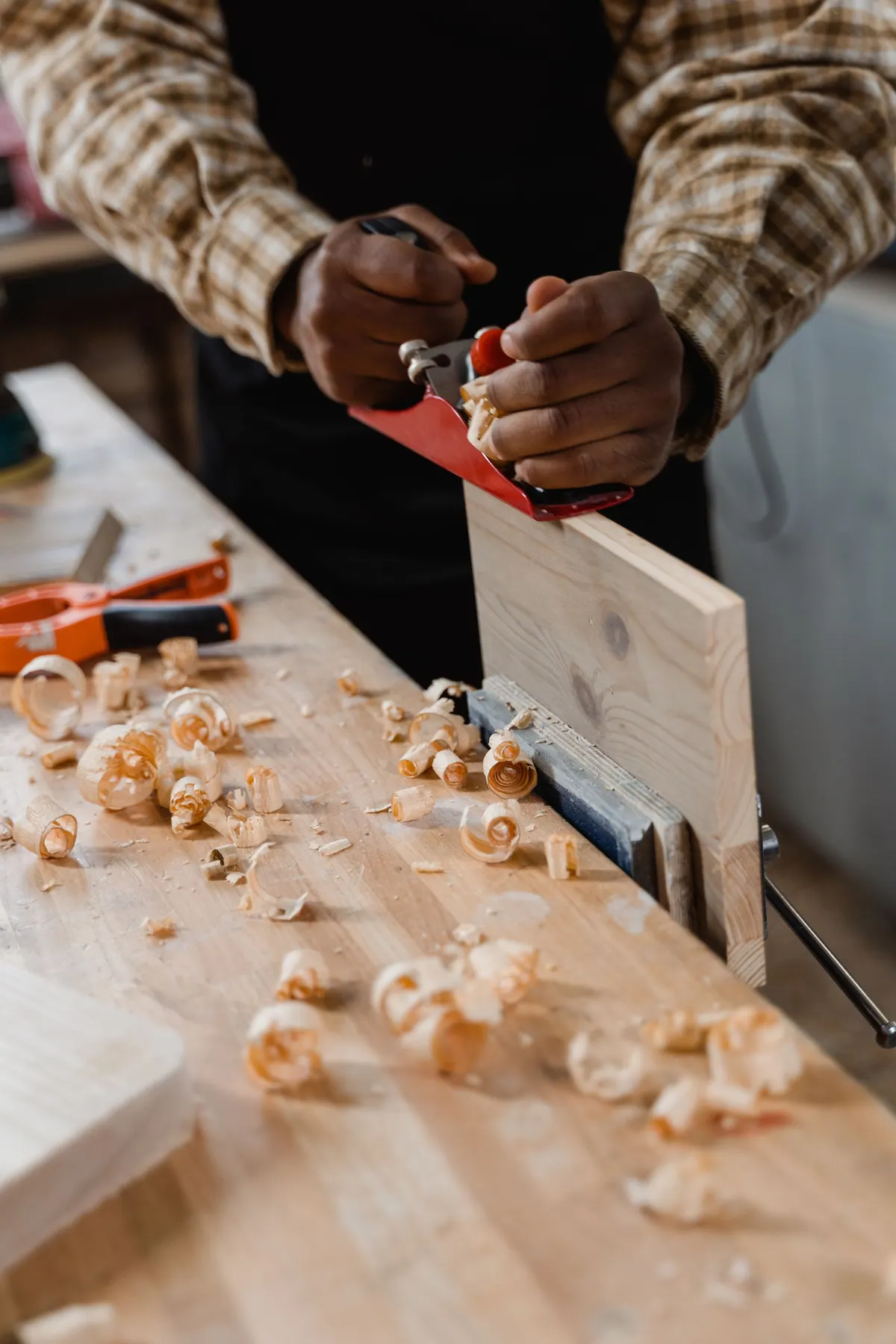 Hands working wood with a chisel, shavings on the bench