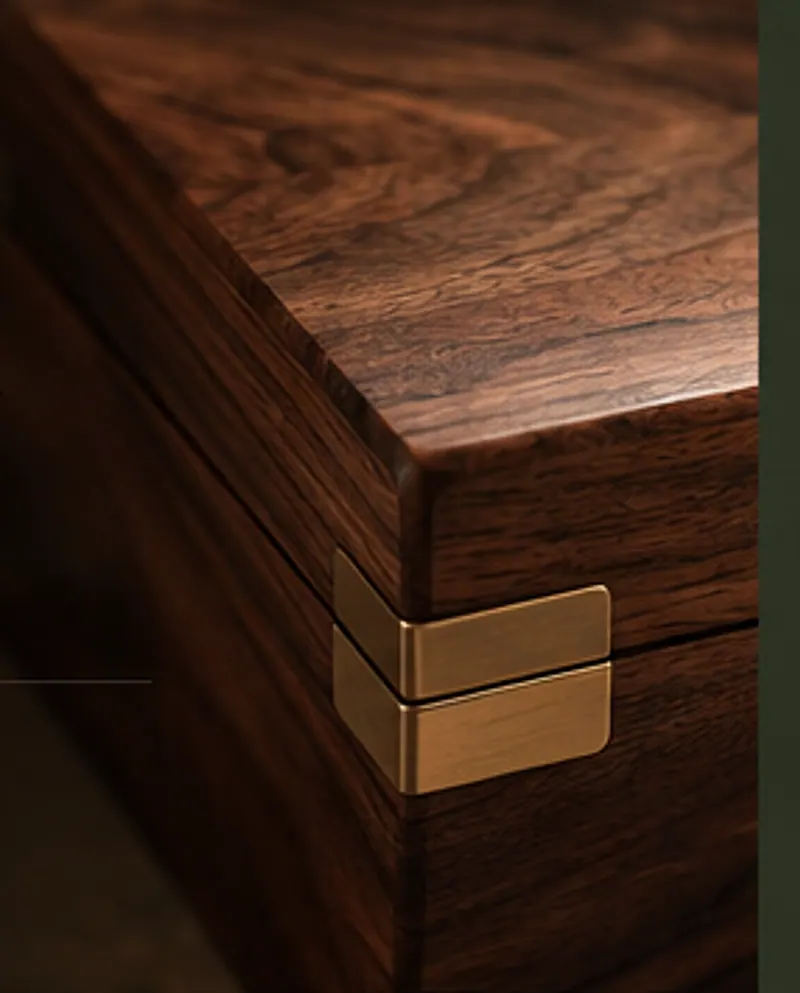 The corner of a walnut box with a brass clasp, lit from above